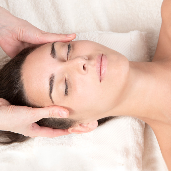 Soin du visage en institut, gestes apaisants associés aux bienfaits d’une crème postbiotique.